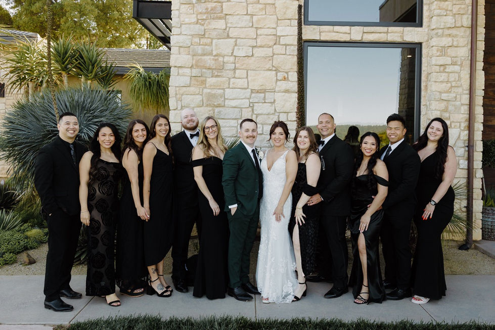 a bride and groom pose with their wedding party in front of a stone building