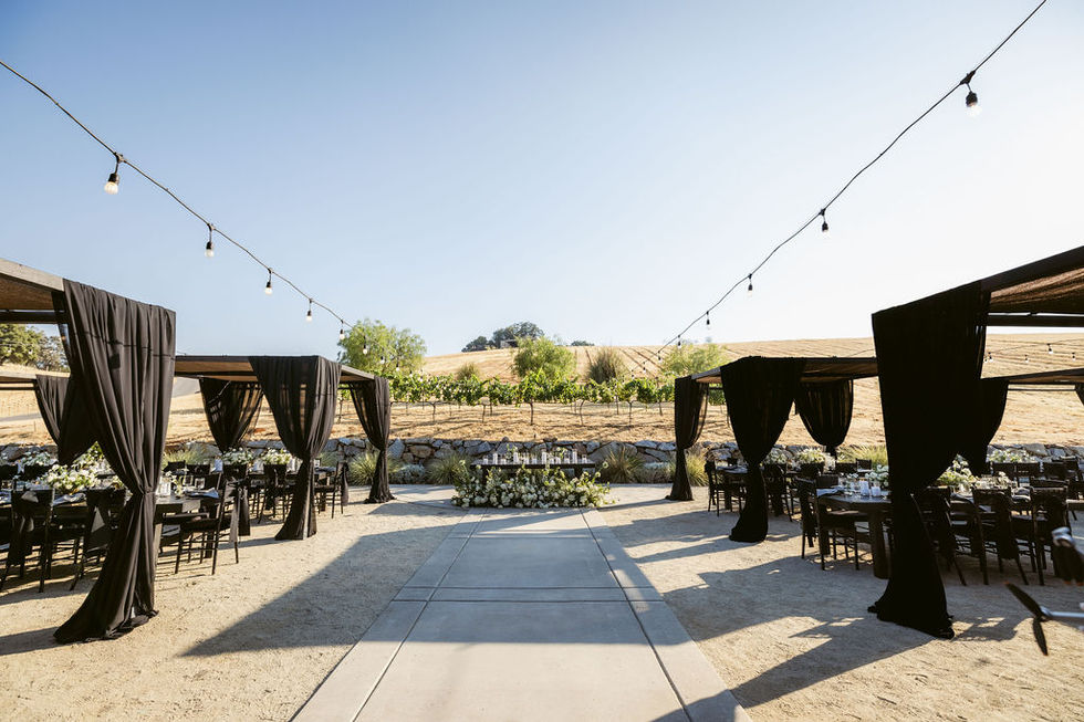 a table with flowers and candles in front of a vineyard