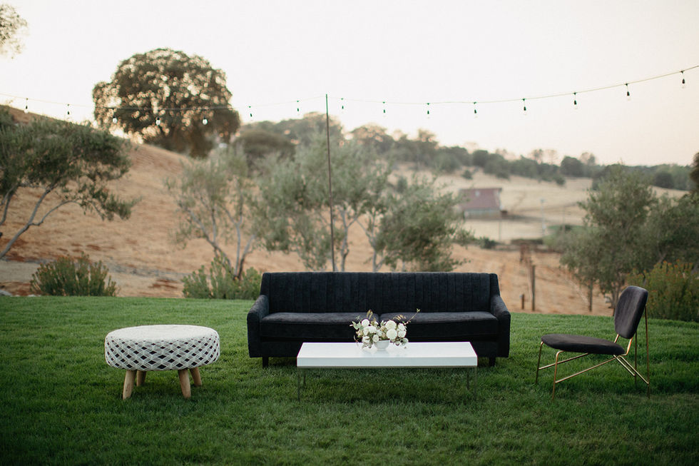 a black couch sits in the grass next to a white coffee table