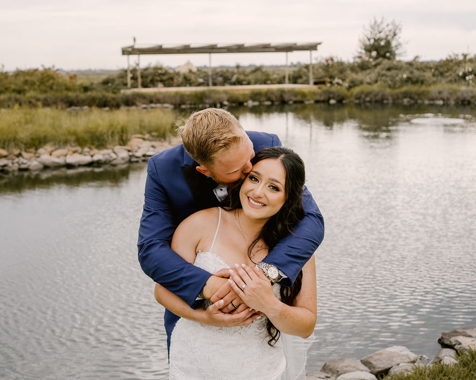 a bride and groom pose for a picture in front of a lake