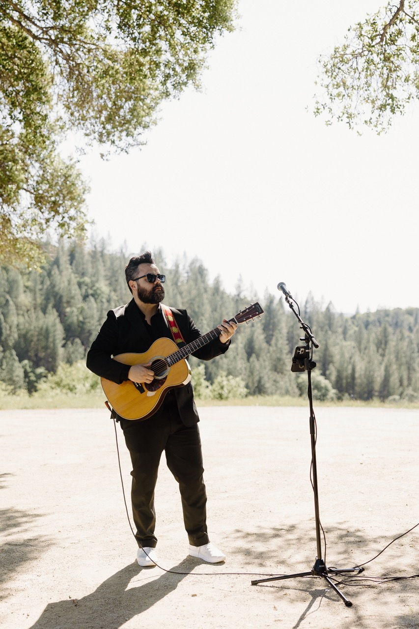 a man playing a guitar in front of a microphone