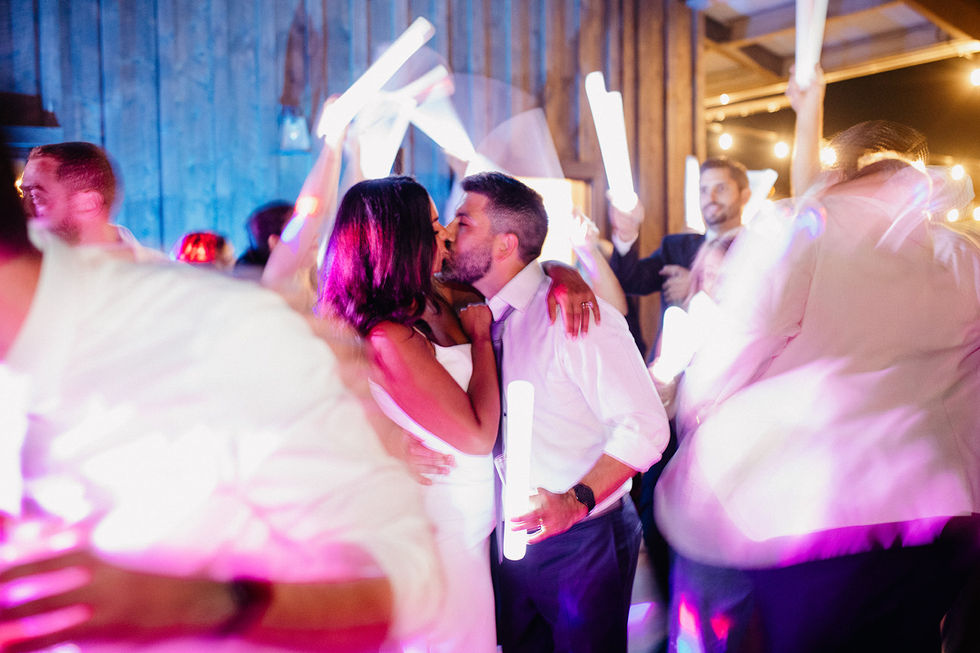 a bride and groom kiss while holding light sticks