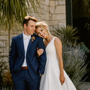 a bride and groom posing for a picture in front of a stone building