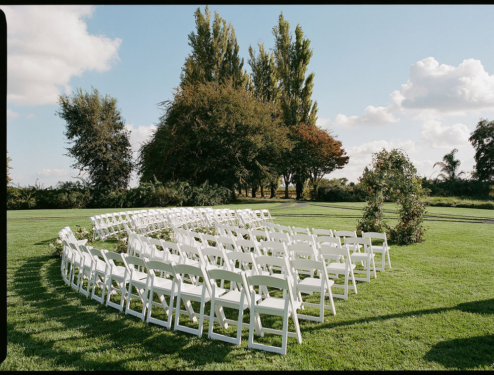 rows of white folding chairs are arranged in a circle in the grass