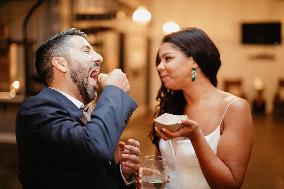 a man is feeding a piece of cake to a woman who is holding a glass of water