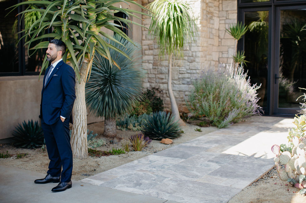 a man in a suit stands in front of a stone building