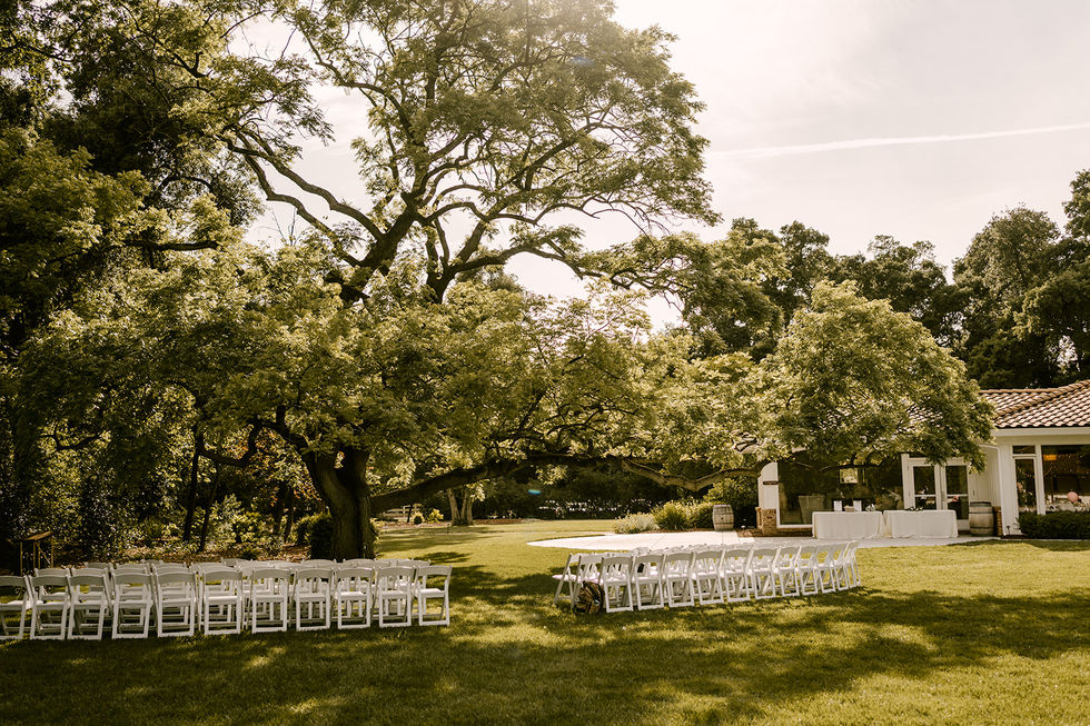 a row of white folding chairs in a grassy field