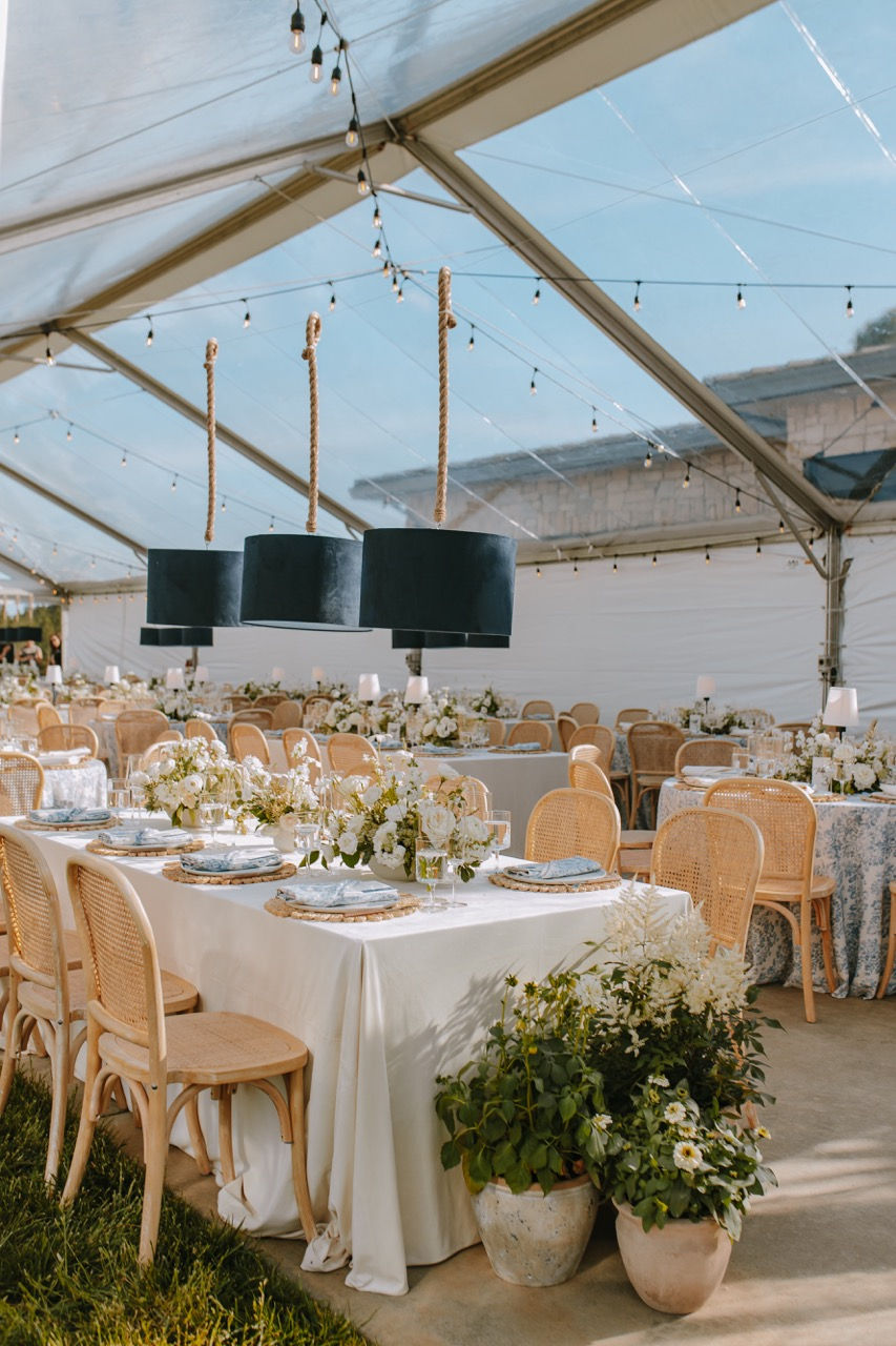 a clear tent with tables and chairs set up for a wedding reception