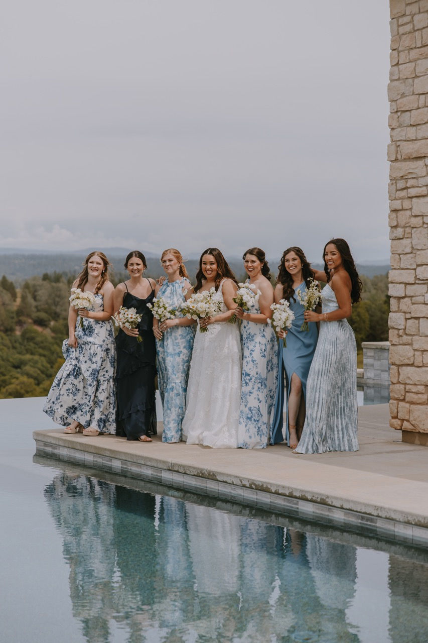 a bride and her bridesmaids pose by a pool