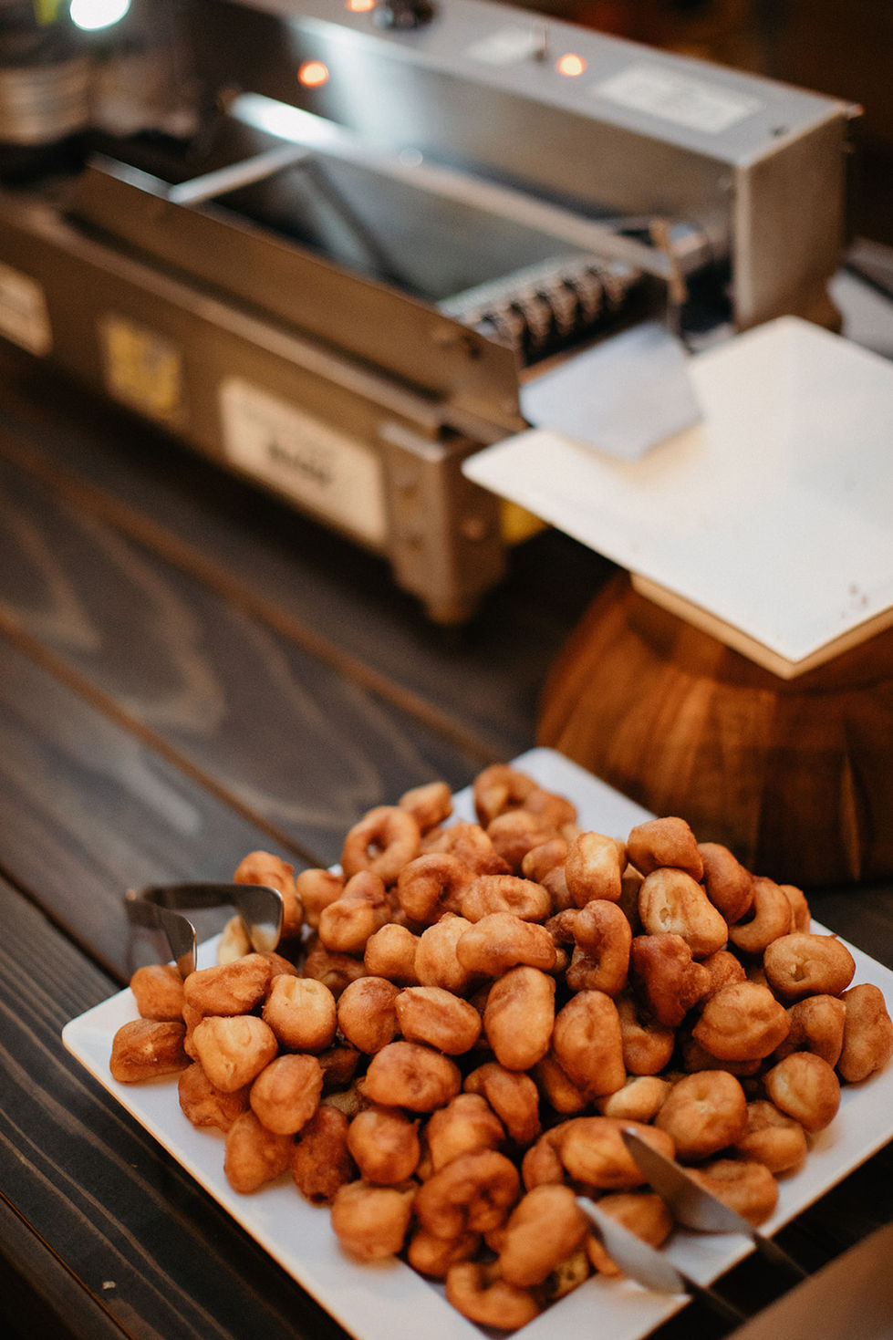 a plate of fried donuts sits on a wooden table
