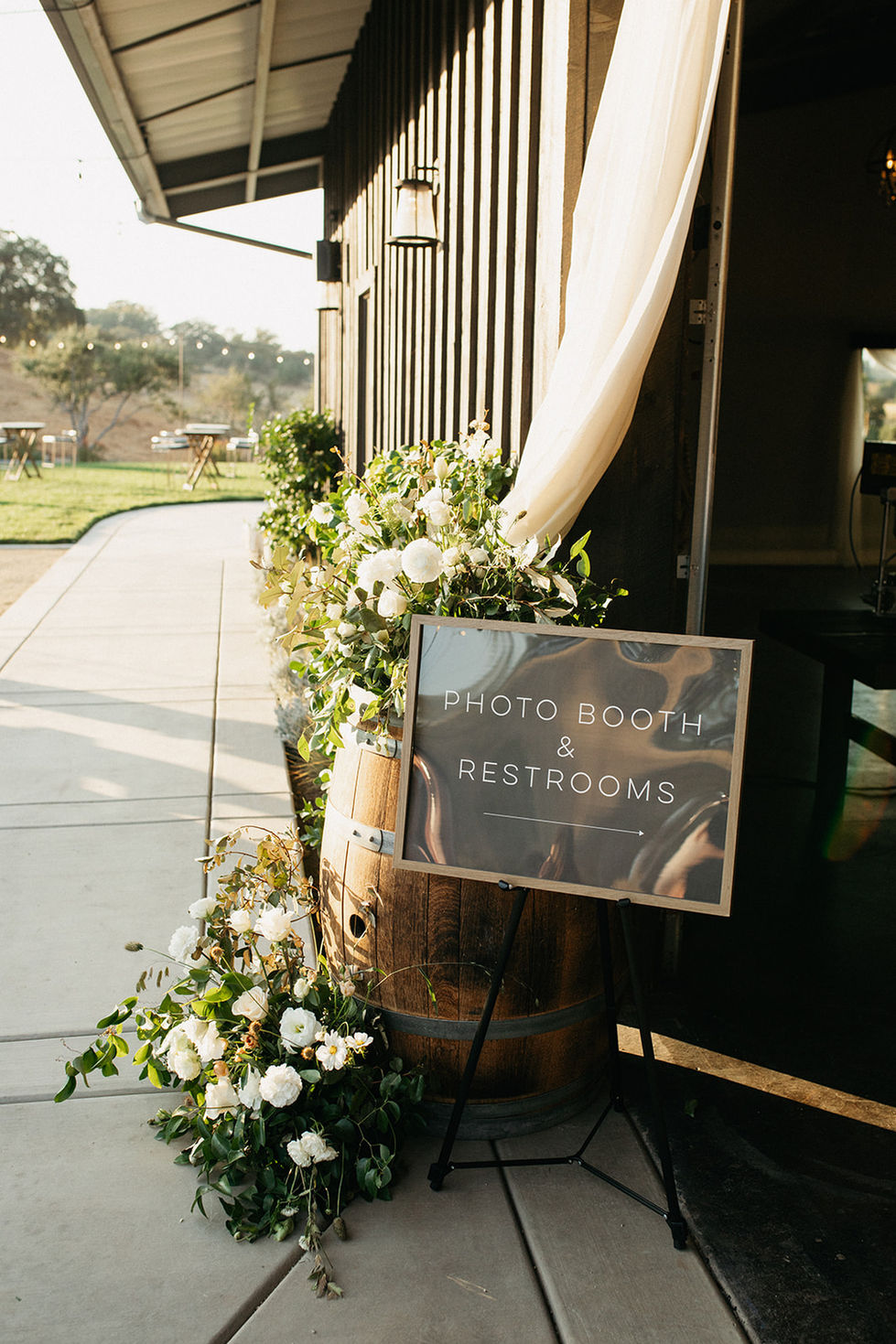 a photo booth and restrooms sign on a wooden barrel