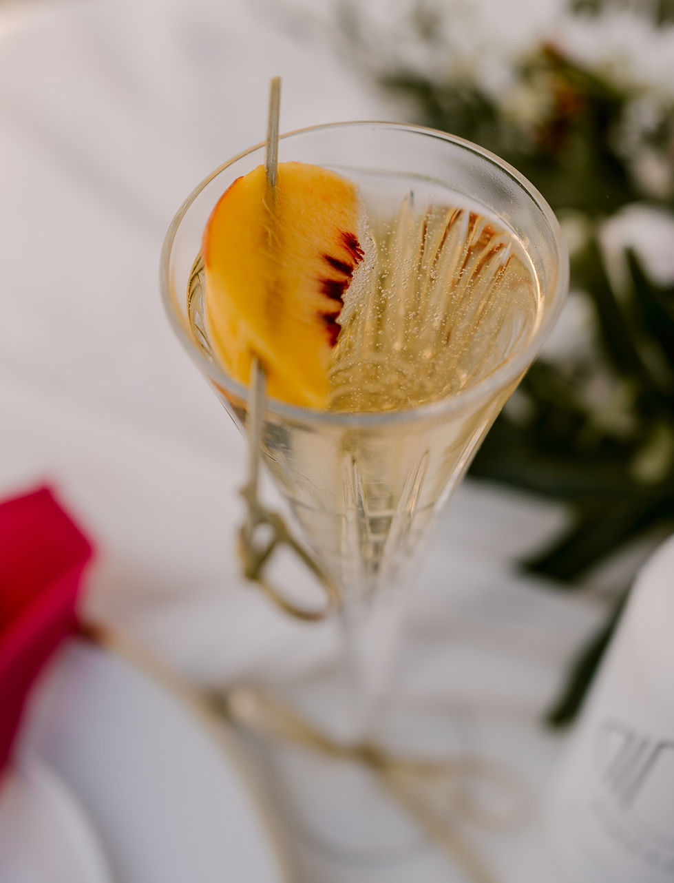 a glass of champagne with a slice of peach in it