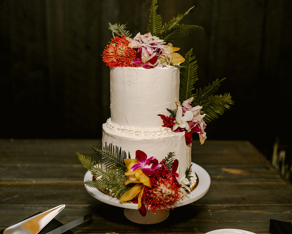 a white cake with flowers and ferns on top