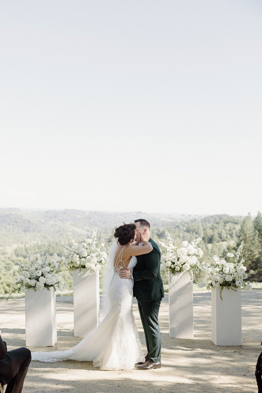 a bride and groom kissing in front of white flowers