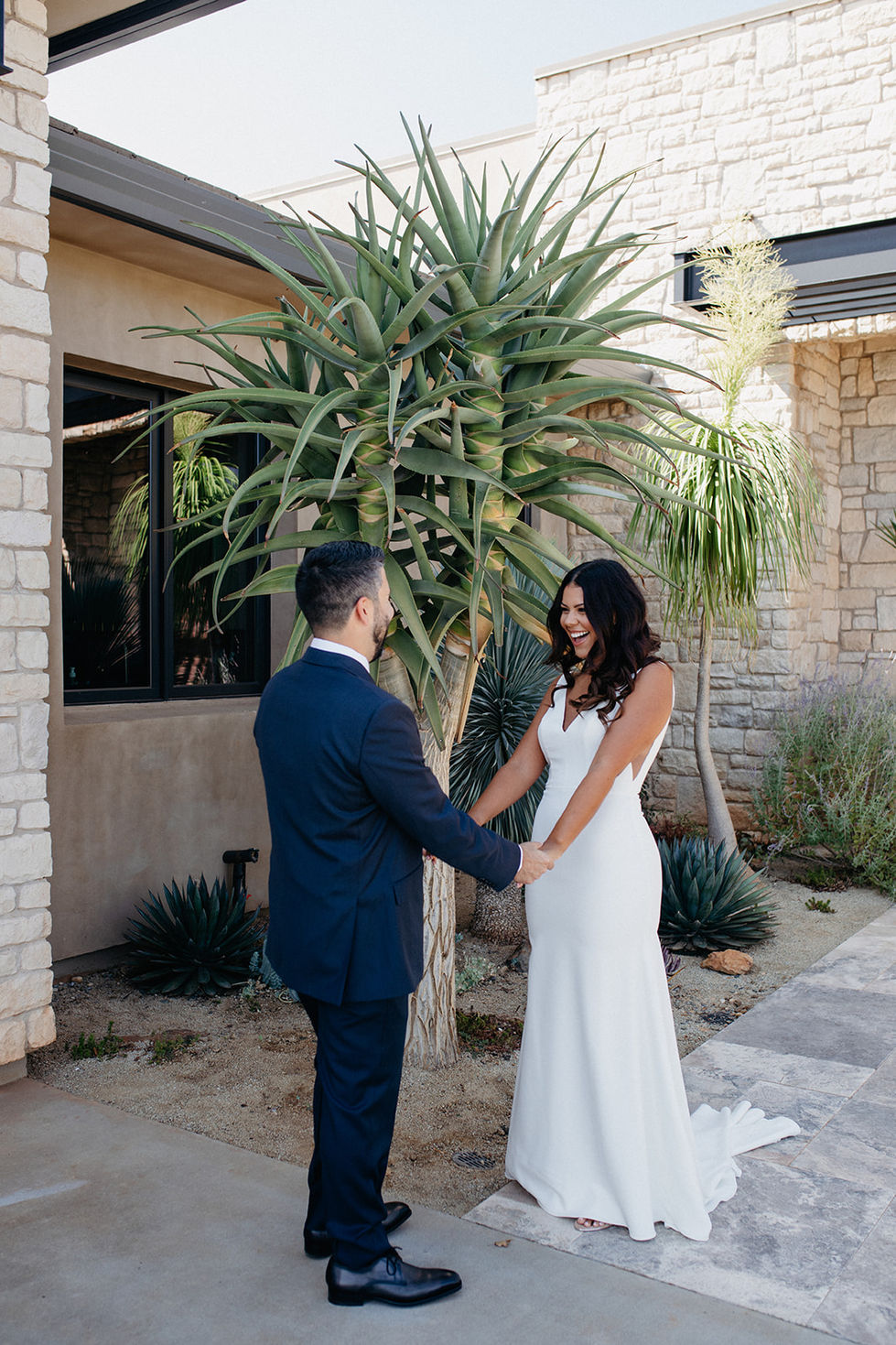 a bride and groom hold hands in front of a palm tree