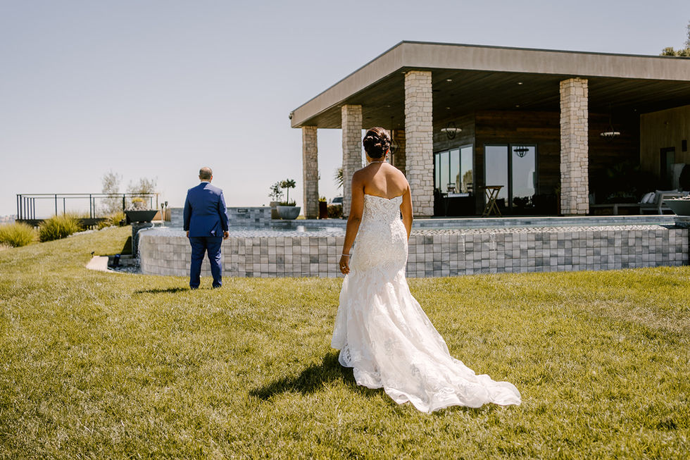 a bride and groom are standing in the grass in front of a building