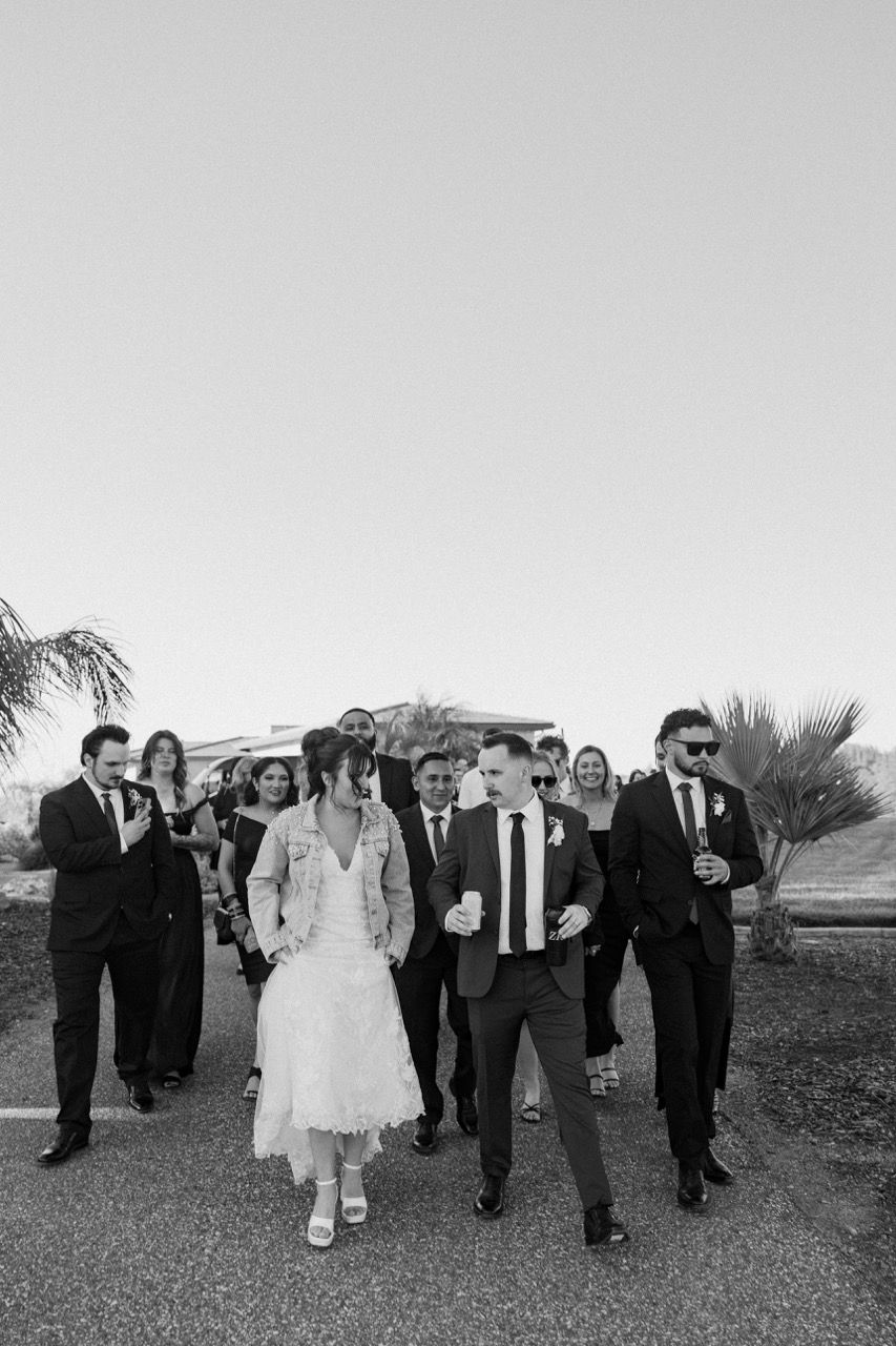 a bride and groom are walking with their wedding party