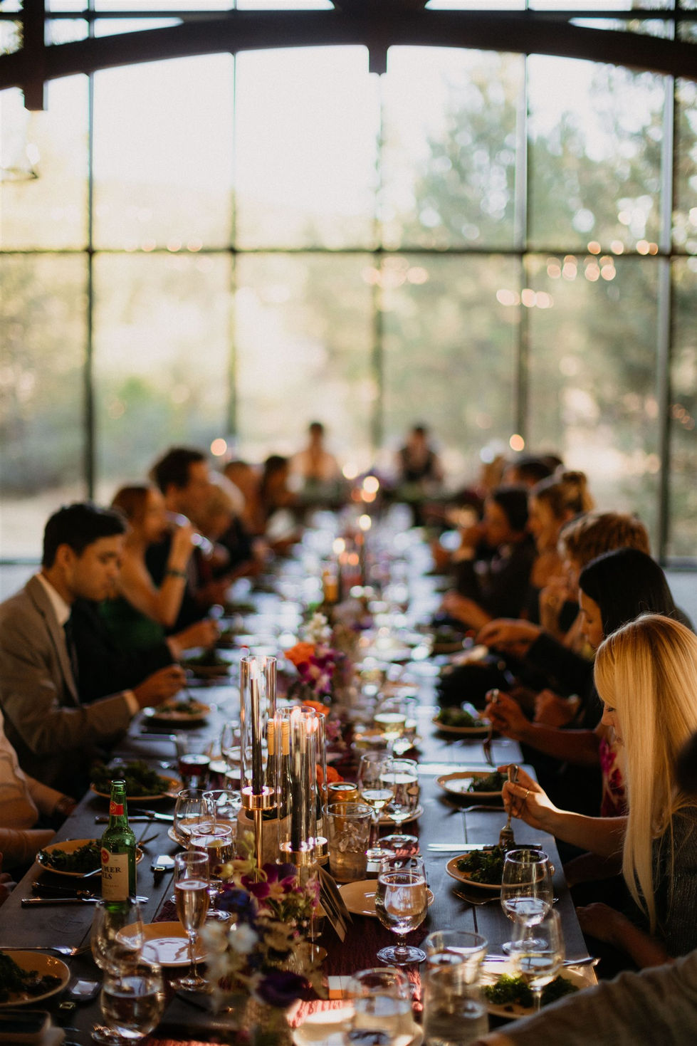 a group of people are sitting at a long table eating
