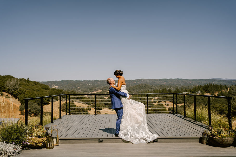 a man is holding a woman in his arms on a deck