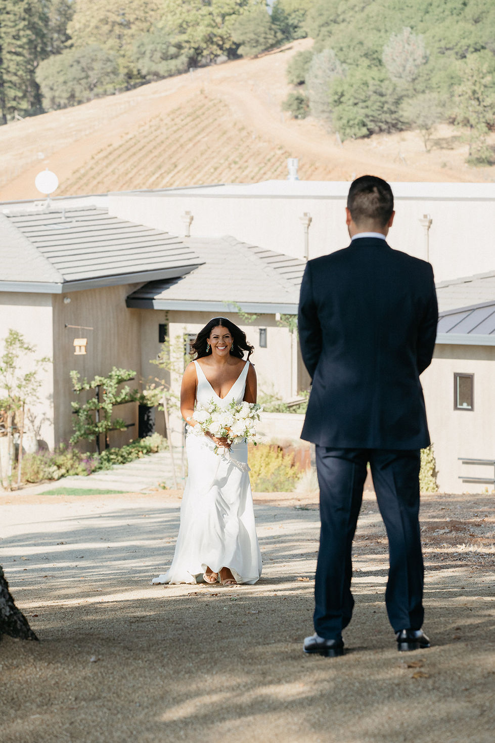 a bride in a white dress stands in front of a man in a suit