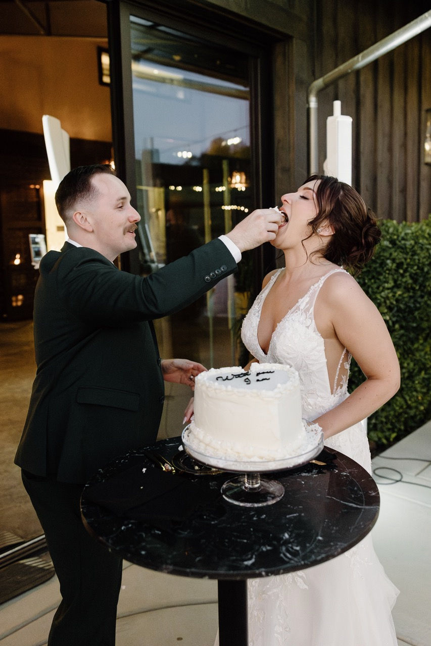 a bride and groom are feeding each other a piece of their wedding cake