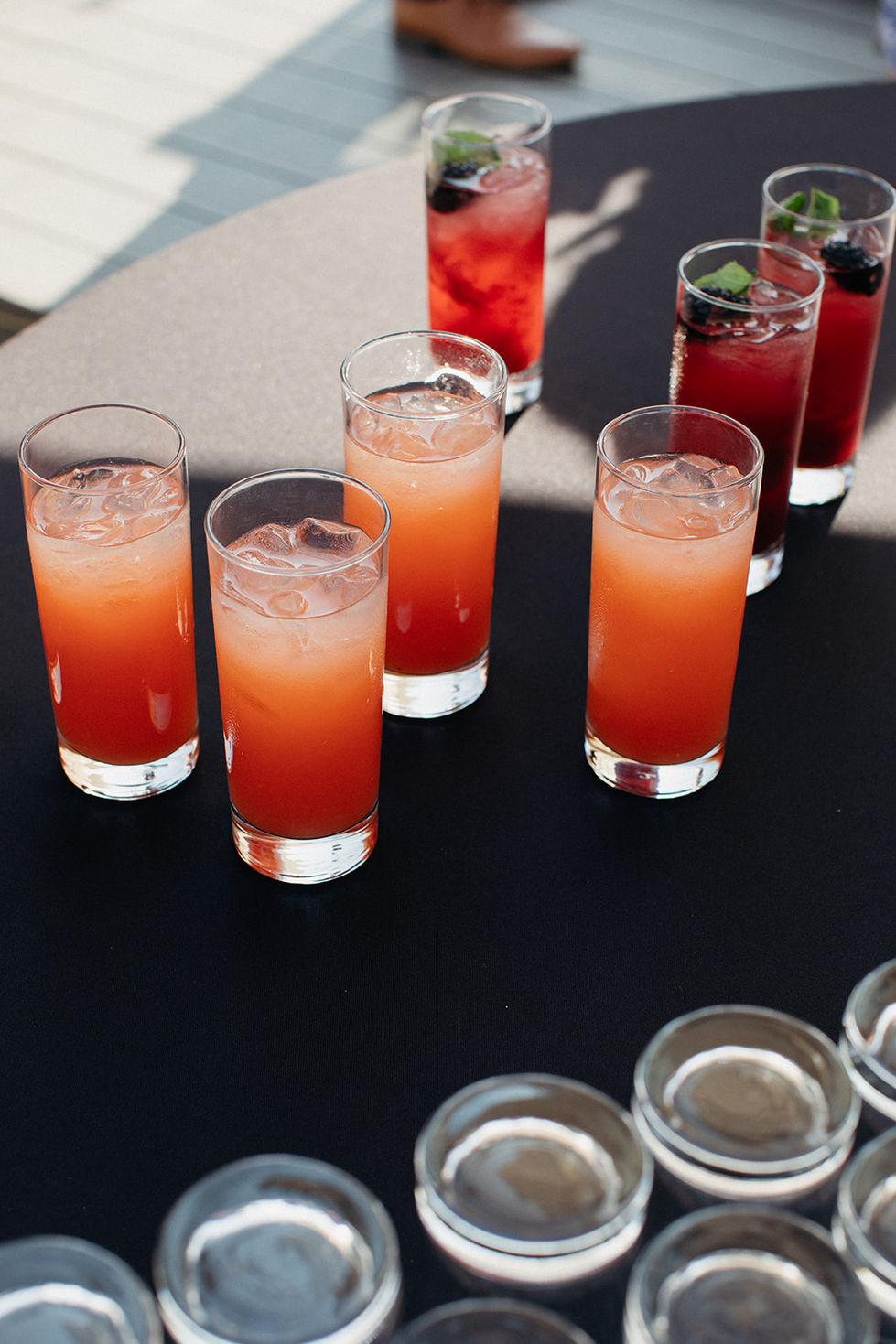 a row of tall glasses filled with red liquid and ice