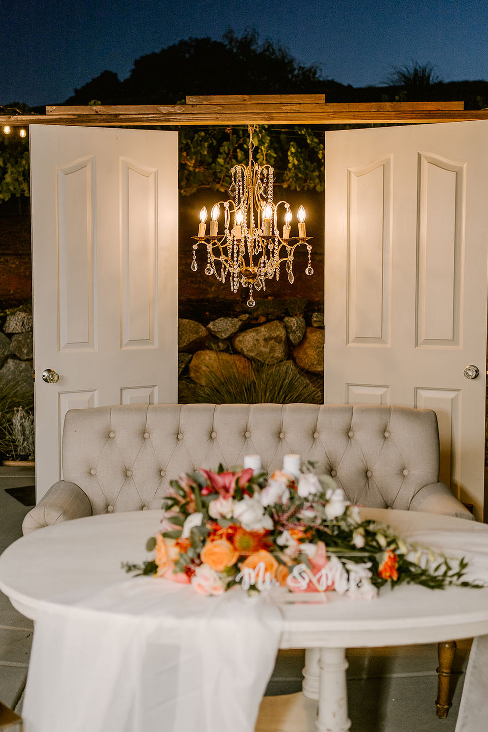 a chandelier hangs above a couch with flowers on it