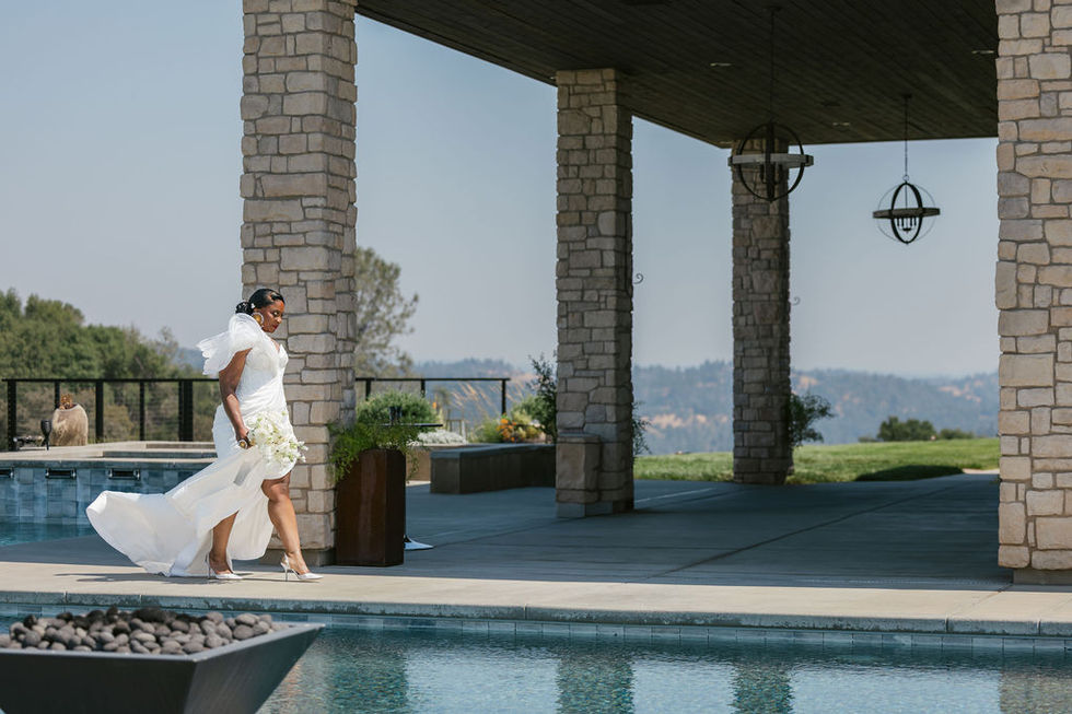a woman in a white dress is walking by a pool