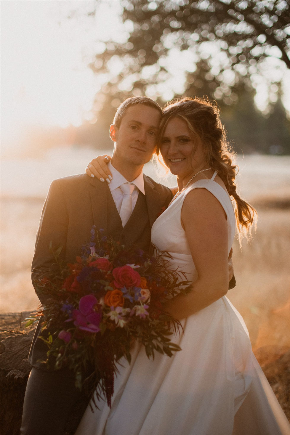 a bride and groom pose for a picture with the bride holding a bouquet of flowers