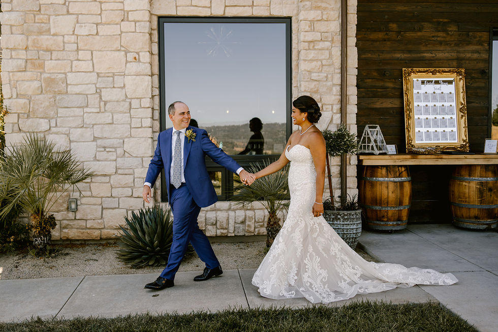 a bride and groom holding hands in front of a brick building