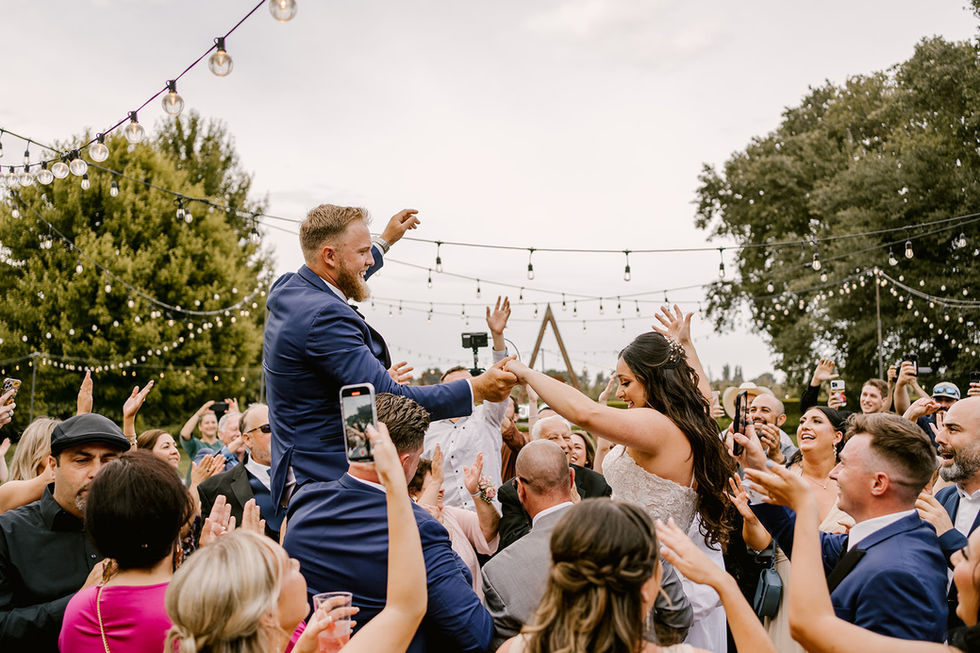 a bride and groom are being lifted in the air by their wedding guests