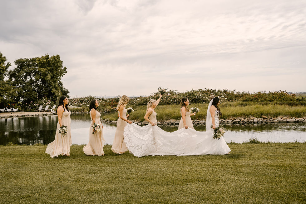 a bride and her bridesmaids are walking by a body of water