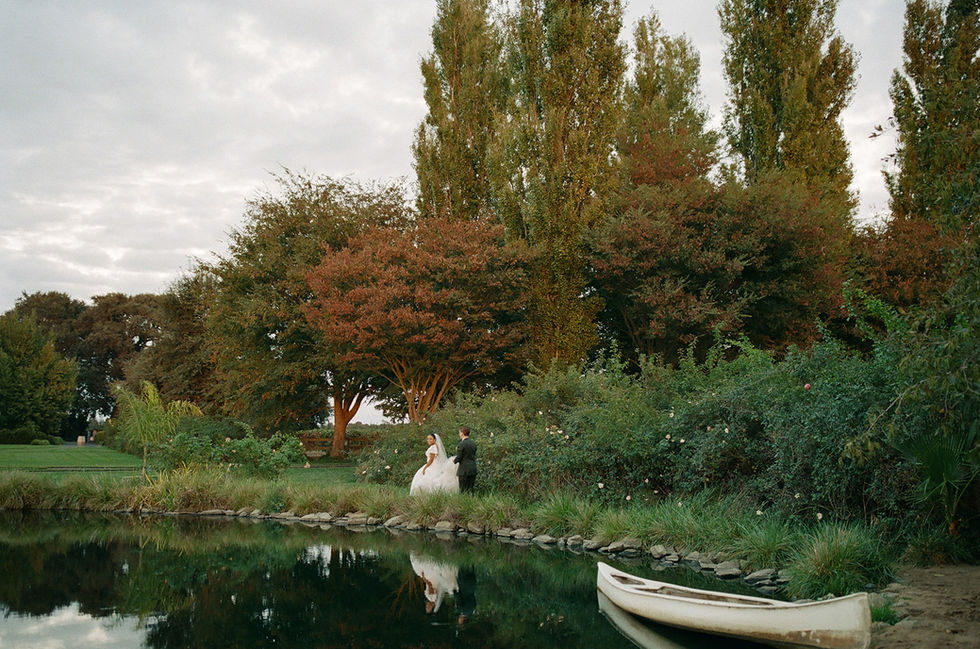 a bride and groom are standing next to a lake
