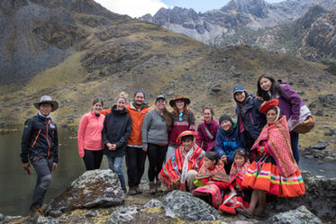 A group of about 10 people from the weaving non-profit posing in from of a lake