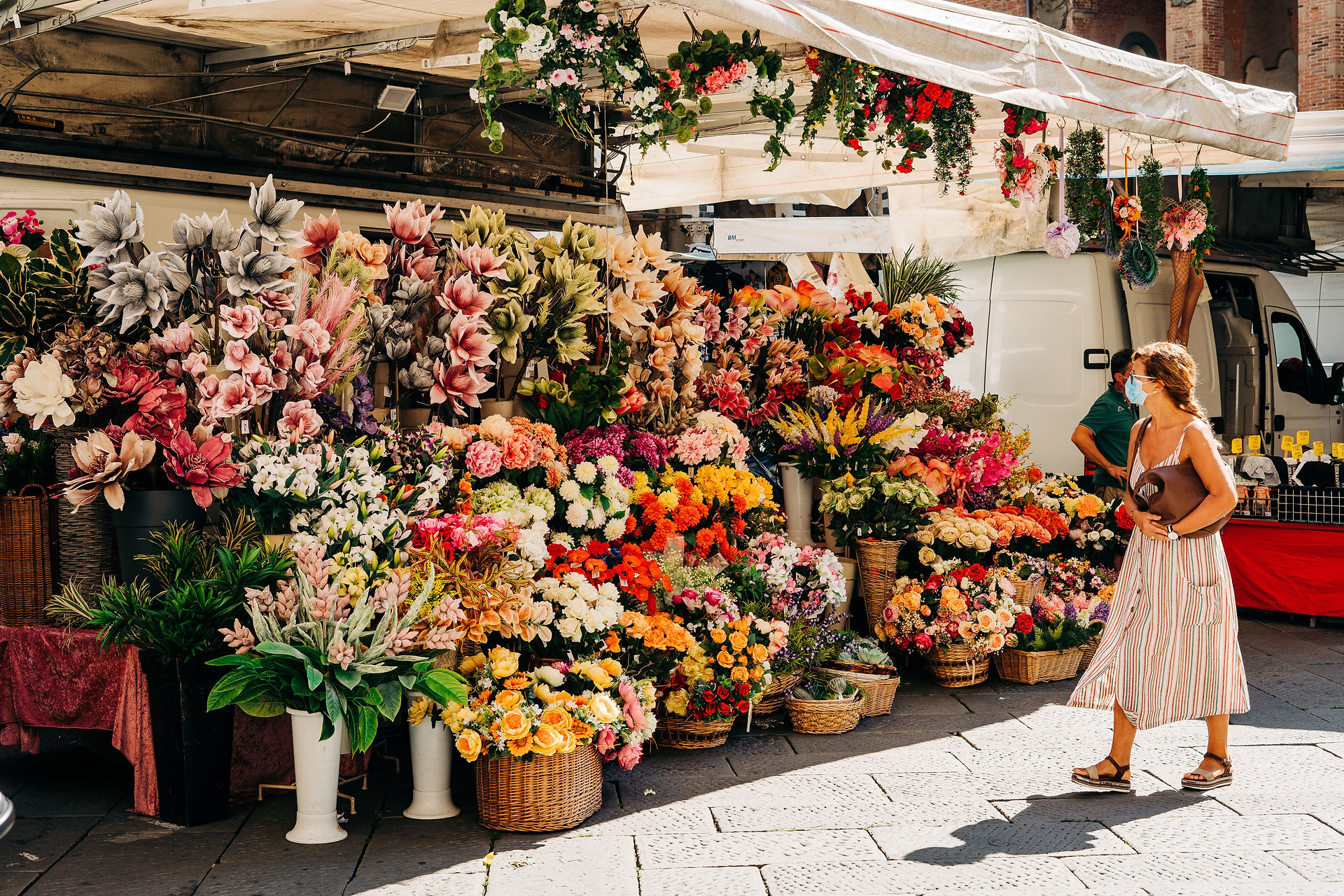A woman walking by a floral shop with lots of flowers