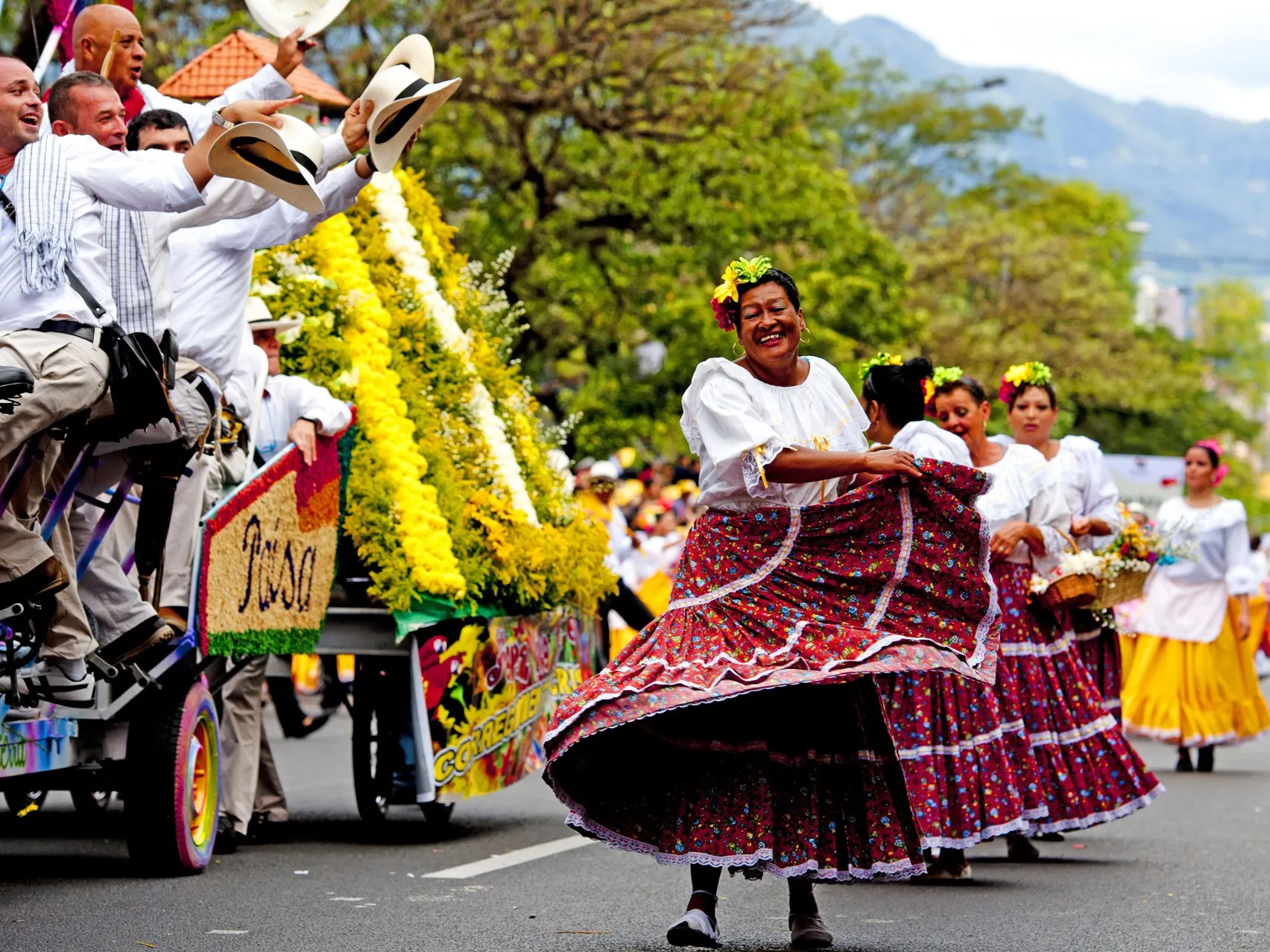 A woman in a large colorful skirt dancing in the street as part of a flower festival