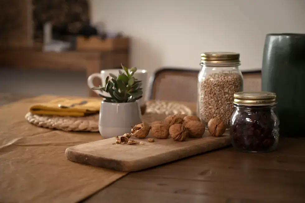 Wooden cutting board with walnuts and glass jars on a rustic kitchen table