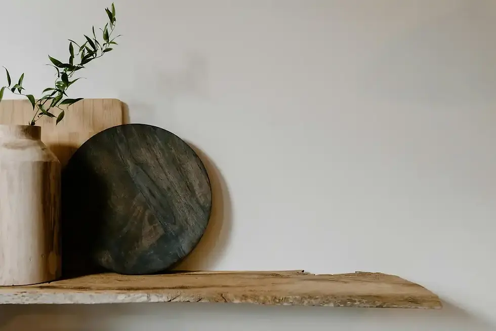 Minimalist Japandi wall decor: Floating reclaimed wood shelf with a decorative wooden vase, dark circular tray, and a green botanical branch.