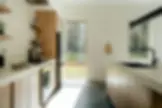Japandi open-plan kitchen with light oak cabinets, concrete floor, and oval dining table natural textures 2026