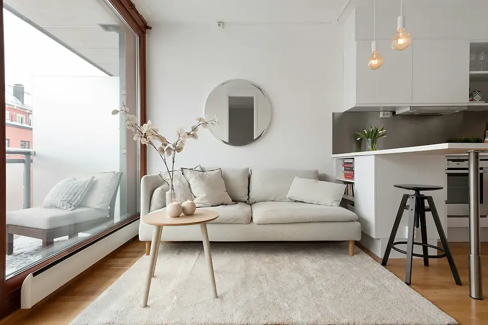 Small apartment open plan living room with neutral sofa round mirror rug-defined zone wood coffee table and warm pendant lighting