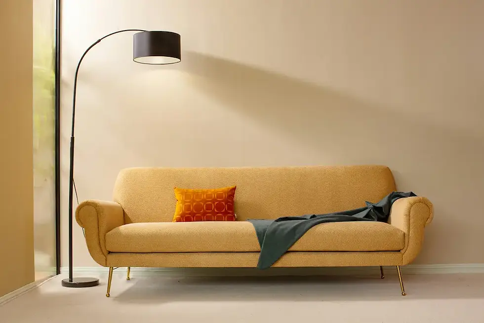 Mustard mid-century sofa styled with an accent pillow and throw under an arc floor lamp