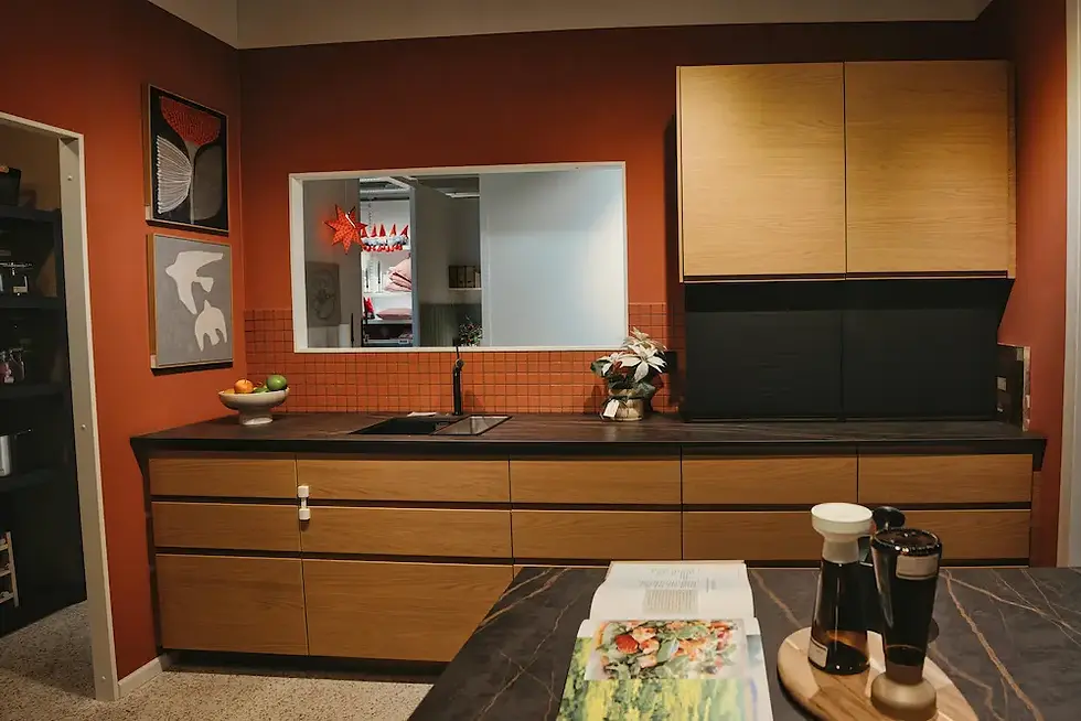 Kitchen with warm terracotta painted walls, natural oak cabinets, and dark stone countertop