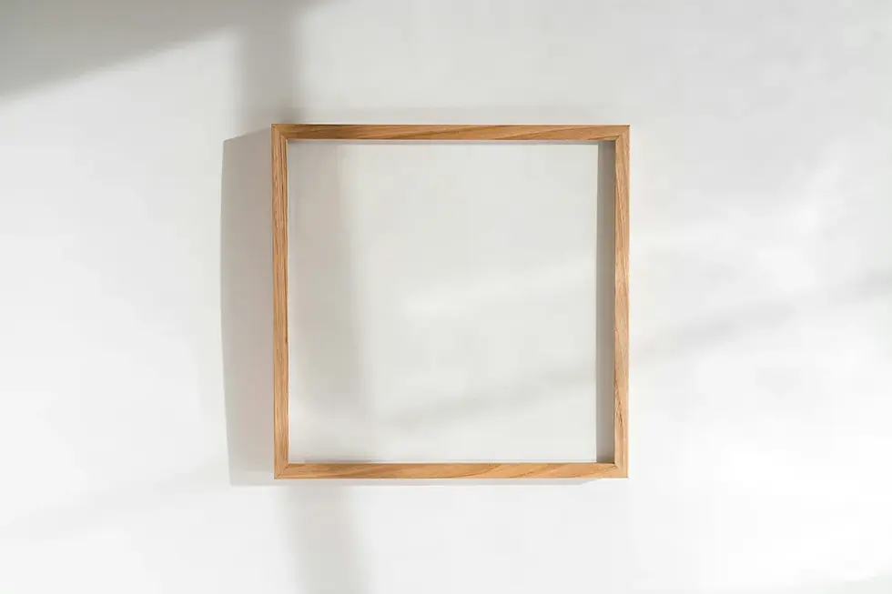Warm wood picture frame on a bright white wall in natural light