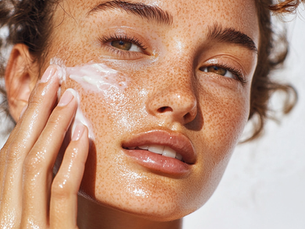 A woman in her 20's applying sun screen on her face