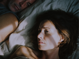woman in bed tired but unable to sleep dues to corisol issues
