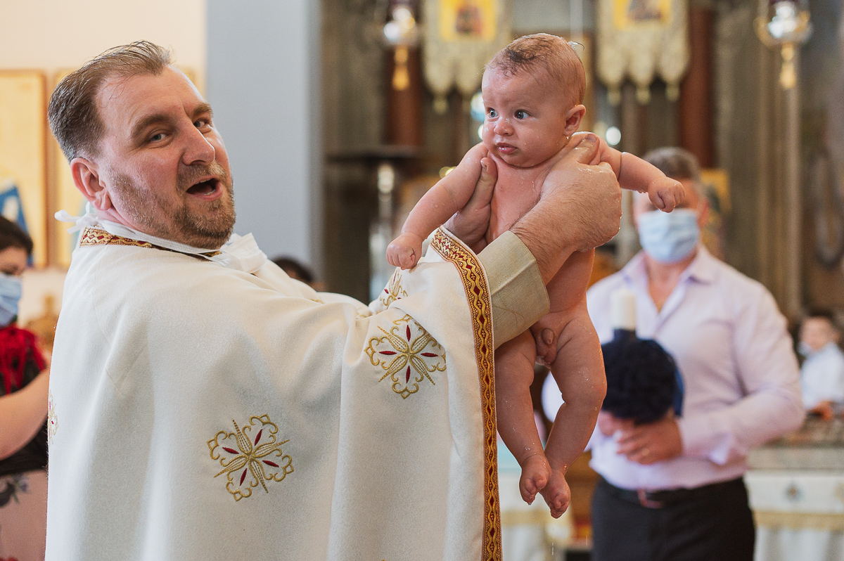 Sacerdote con un bambino durante il rito del Battesimo, Milano