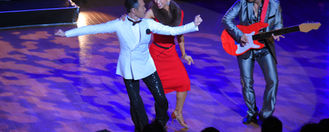 a singer and his lady standing by a guiterist