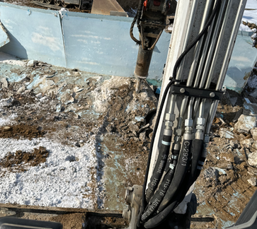 Mini excavator using a hydraulic breaker attachment to break up concrete during a demolition project in Franklin, Indiana.
