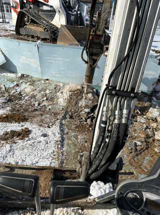 Mini excavator using a hydraulic breaker attachment to break up concrete during a demolition project in Franklin, Indiana.