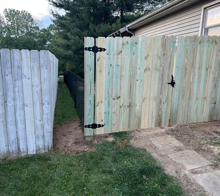 6-foot wood privacy fence with a 4-foot gate connected to 4-foot black chain link fencing enclosing a yard in Ellettsville, Indiana.